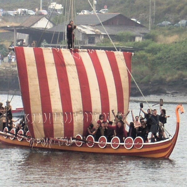Barco vikingo de la fiesta de Catoria, con personas y velas blanca y roja